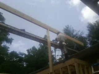 Carpenter setting a ridge beam over a new addition frame — Ice Dam Removal by Roofing Brothers in Fallbrook
