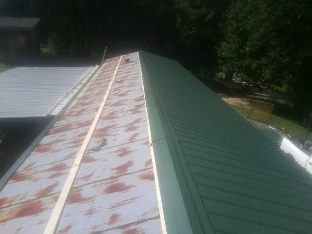 Old rusted panels beside newly installed green metal roofing — Wind Damage Roof Repair by Roofing Brothers in Fallbrook