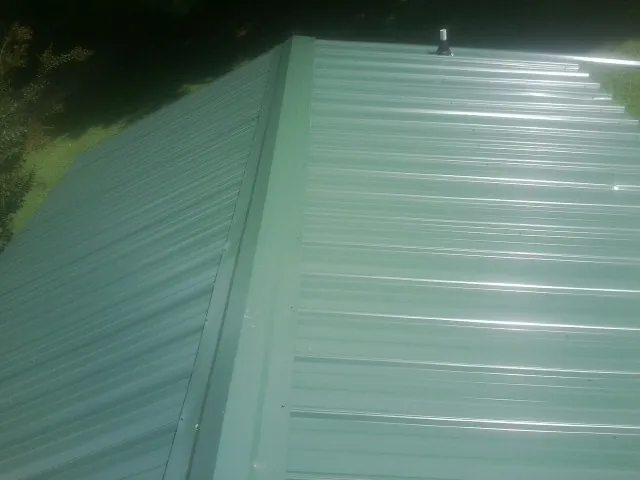 New green metal panels meeting at the ridge of a roof — Flat Roof Repair work by our crew in Fallbrook