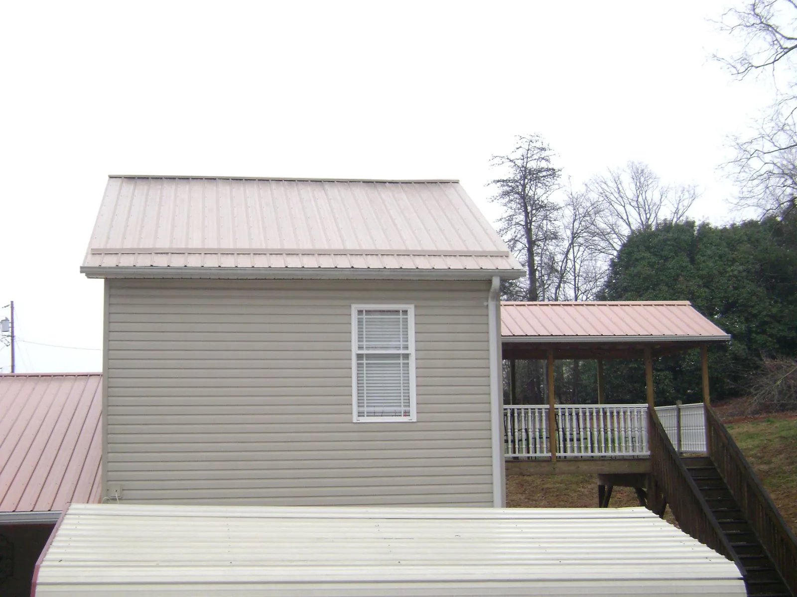 Tan metal roofs on a two story addition and attached porch, from a Roof Replacement job in Fallbrook